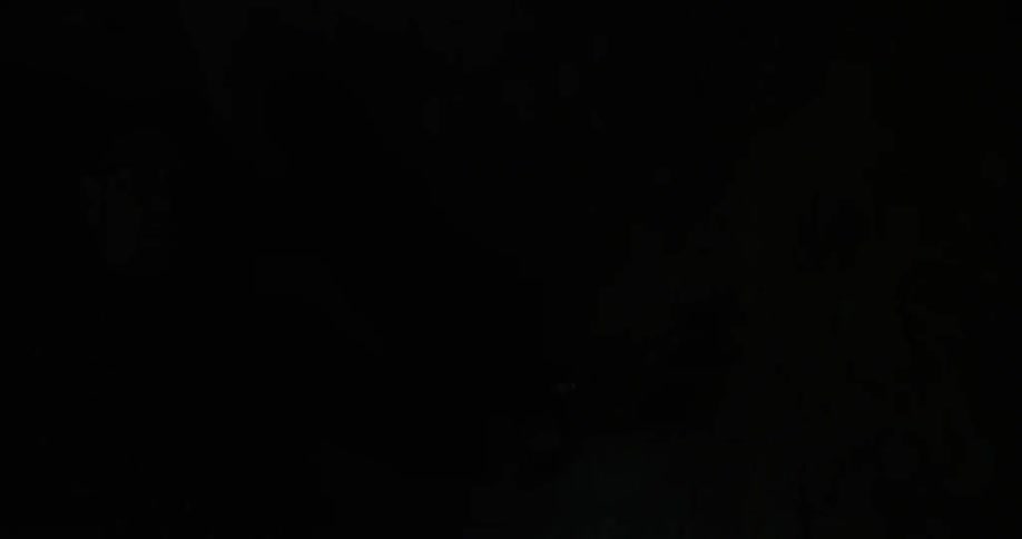 A man touches wall while walking through a dark cave