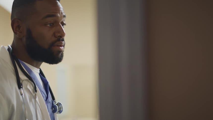 A doctor stands in a room nodding as he speaks