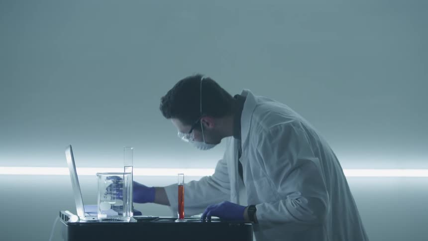 A caucasian male in a lab coat working on an experiment