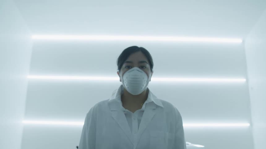 A woman in a room with lots of lights with a mask on