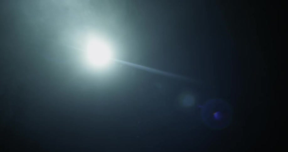 A man is shining a flashlight in a dark cave