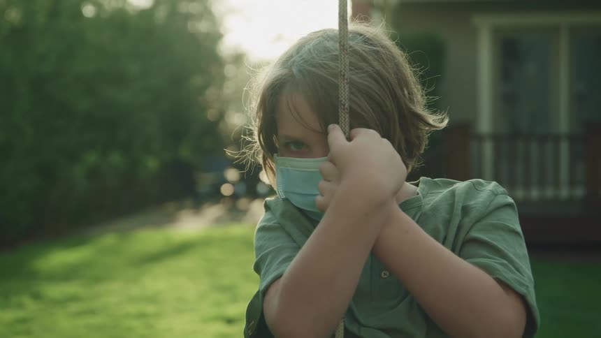 A child is holding onto a rope in the yard