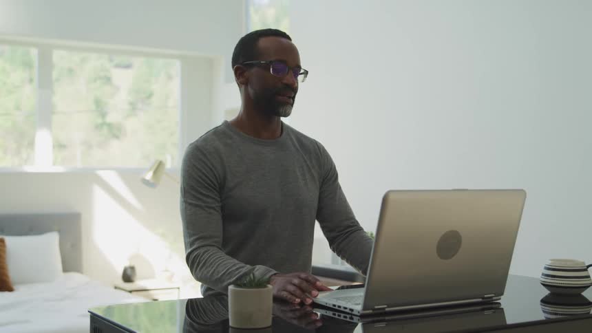 A man is typing on a laptop indoors