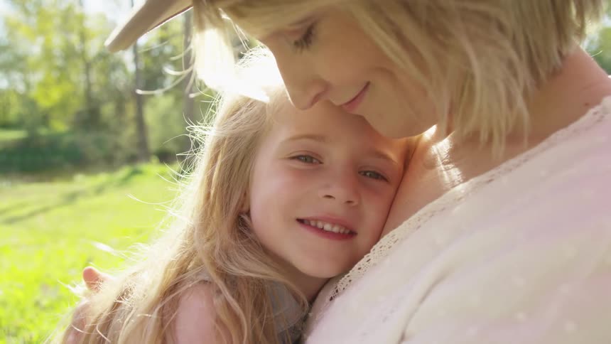 Mother and daughter hugging outdoors under the sun