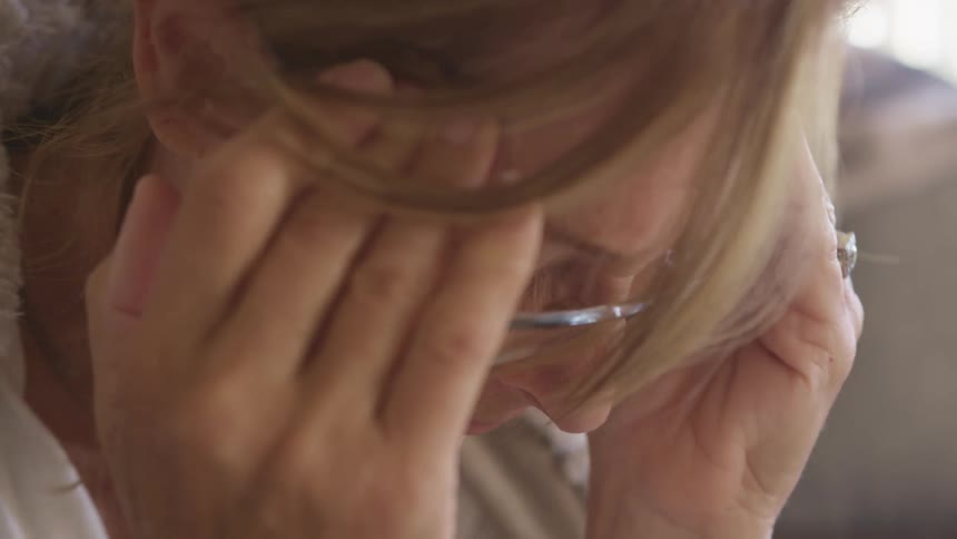 A woman with her eyes closed rubs the side of her head