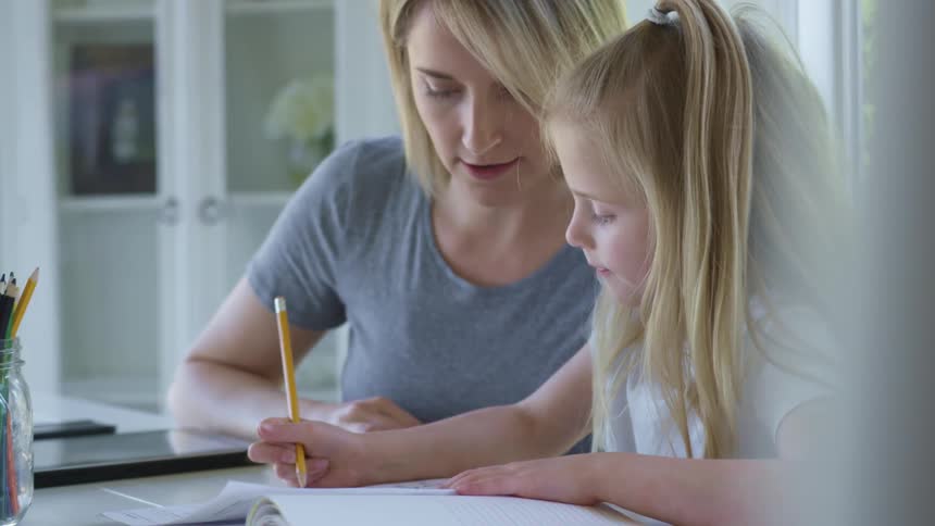 A mother helps her daughter with some school work at home