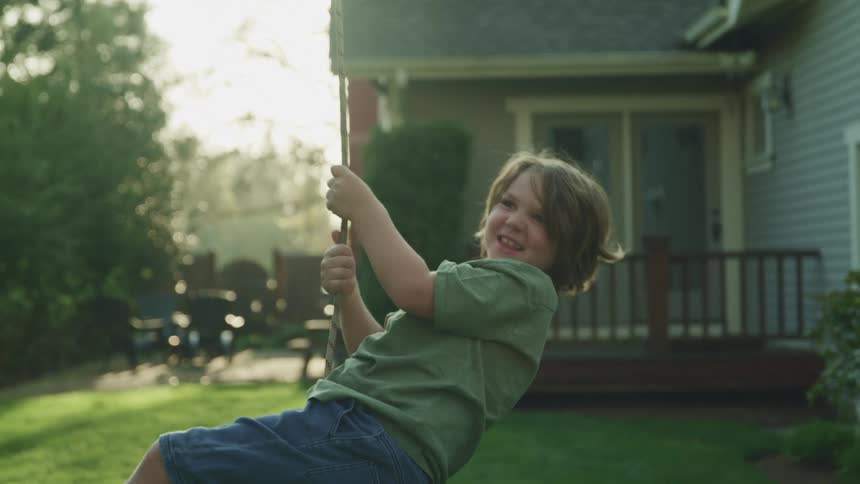 A little boy playing on a swing in his back yard