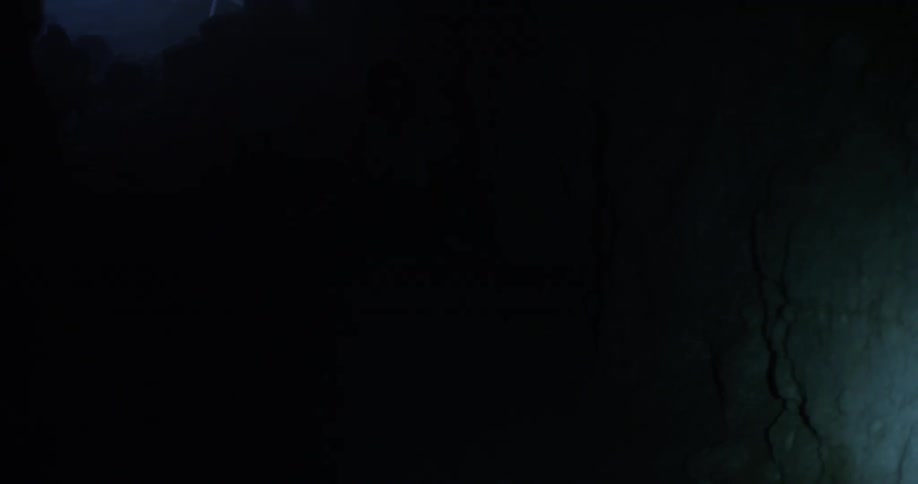 A flashlight shines on the walls of a dark cave