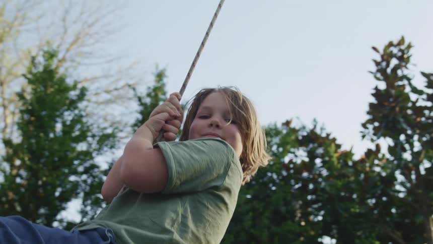 A little boy swinging outside
