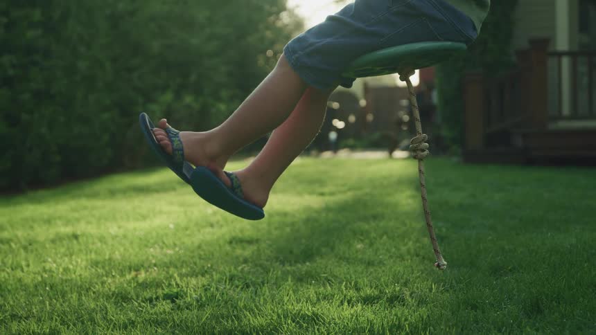 A young boy on a swing in his back yard