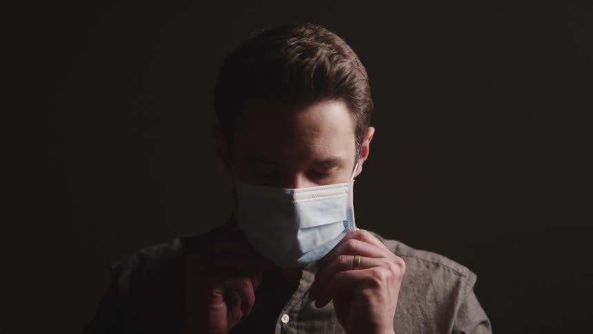 A young man putting a mask on