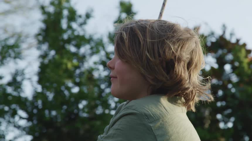 A young boy swinging on a rope swing