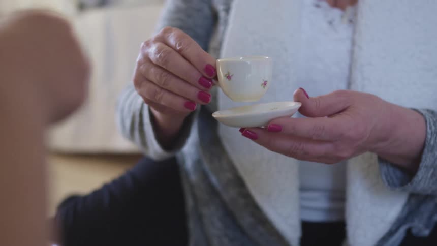 Two woman drinking coffee in small cups on a room at home