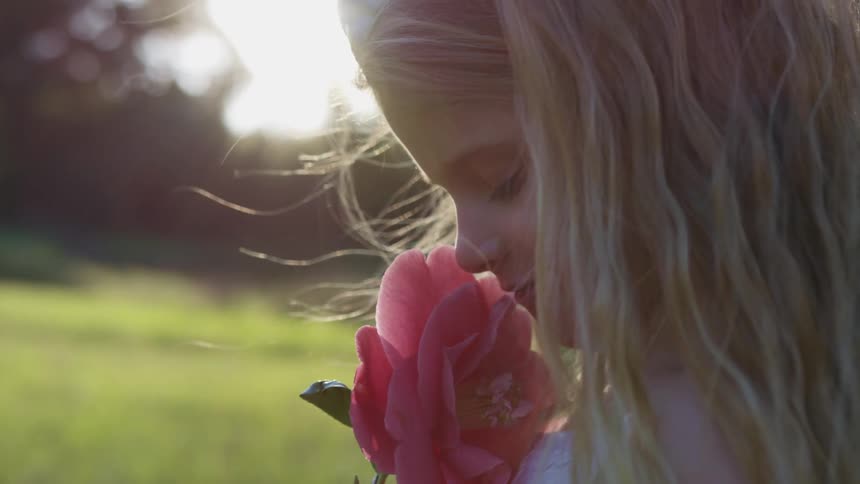 A girl smells a pink flower