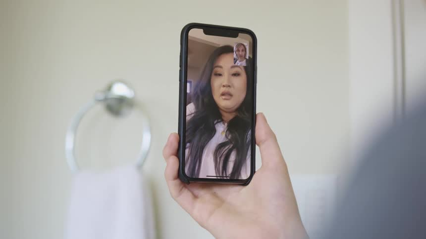 A man and woman communicate with one another through video chat on their smartphones