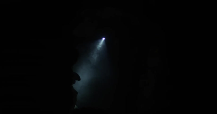 A person uses a flashlight in a dark cave