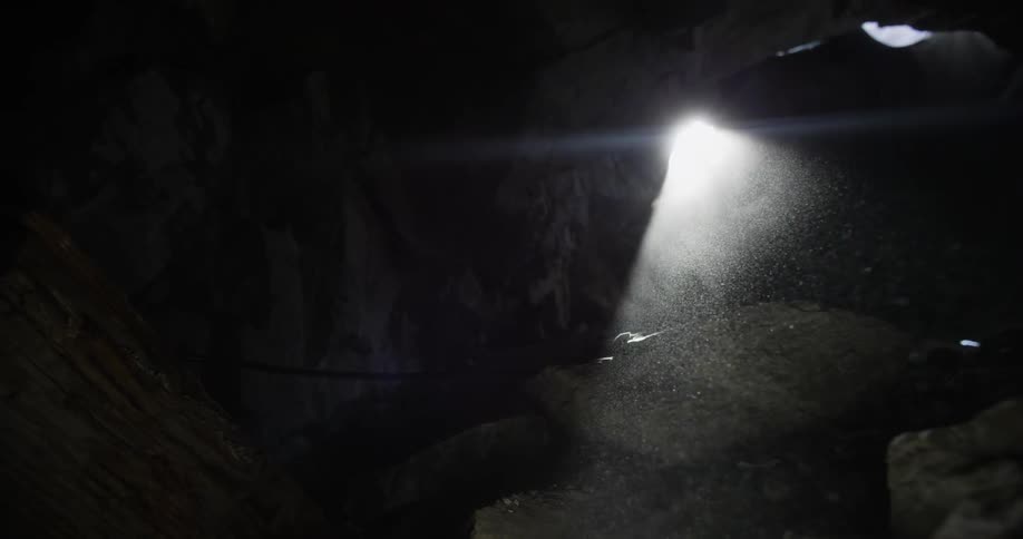 A single light is seen in the distance in a dark area