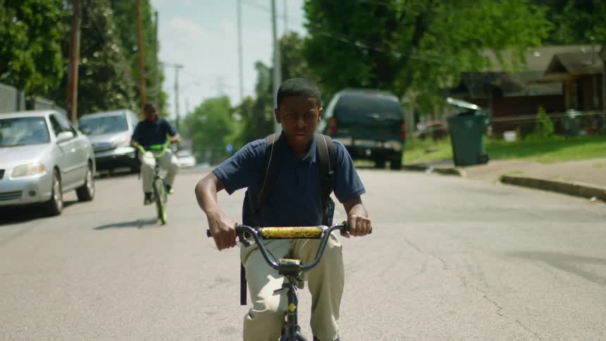A boy rides a bicycle on a neighborhood road