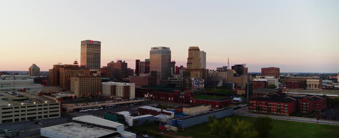 Skyscrapers loom over a city as the horizon begins to redden