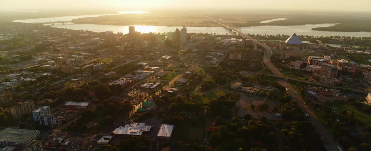 Aerial view of a neighborhood with cars driving and a lake in the distance