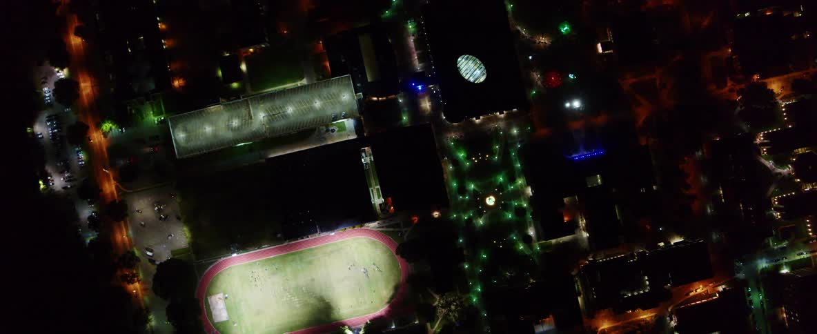 A dense city is illuminated by a variety of street lights and building lights