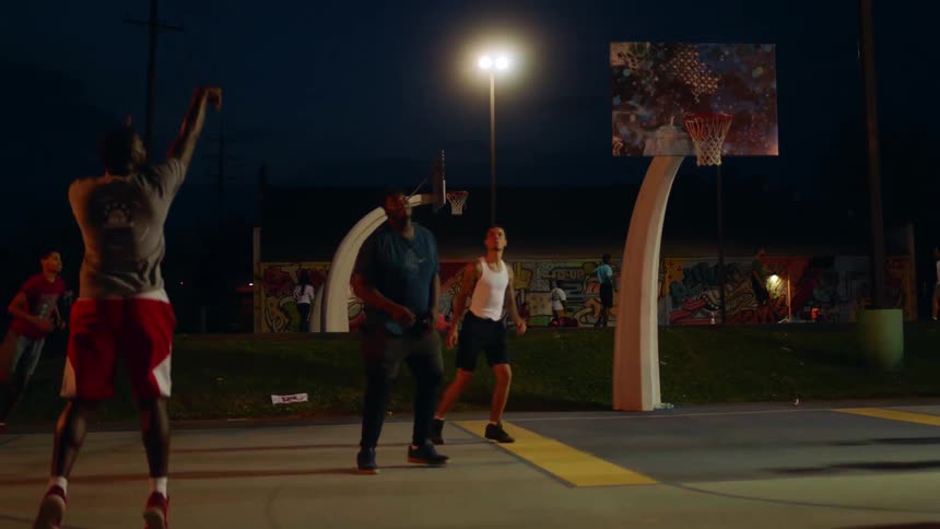 A group of people are playing basketball at night