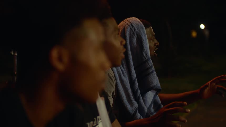 Men sit outside at night as intent spectators