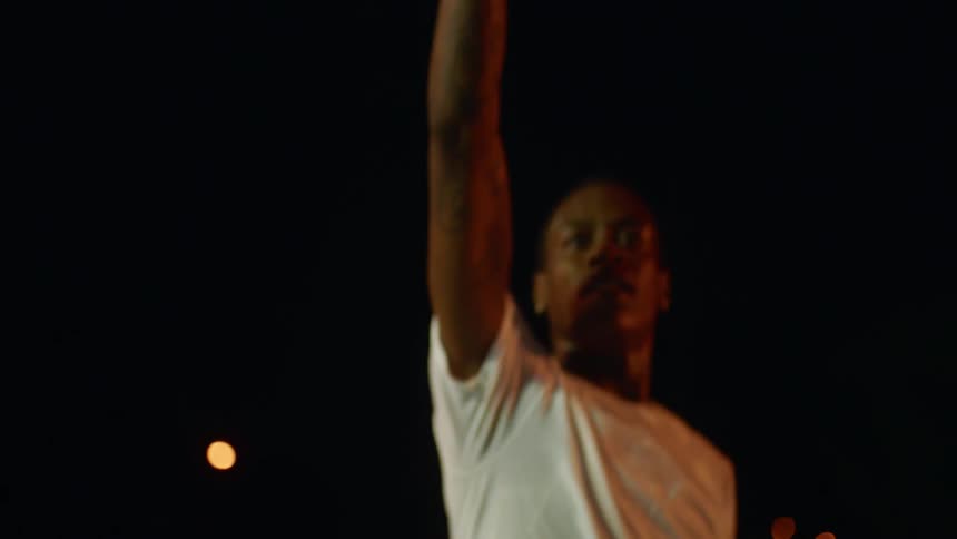 Man takes basketball shot then hops backward gesturing and smiling