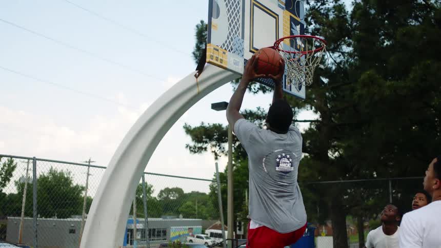 A group of young men play basketball at an outdoor public court