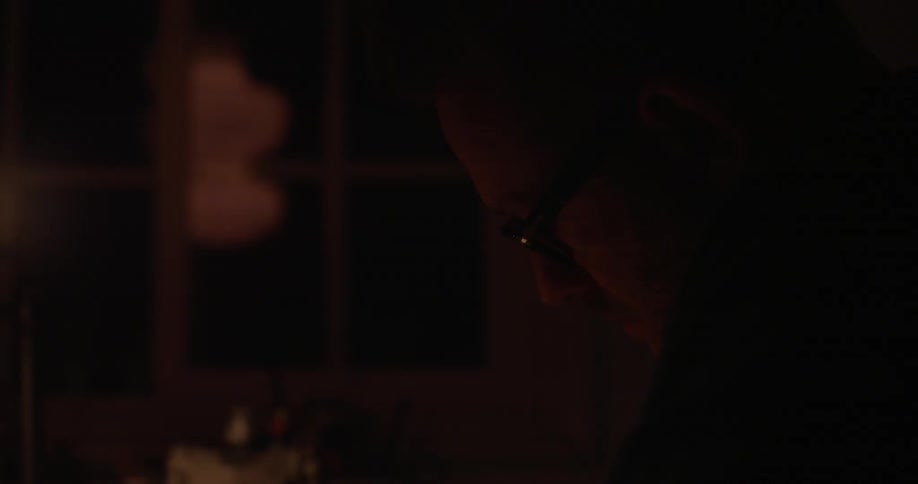A man looking down at something in a dim room