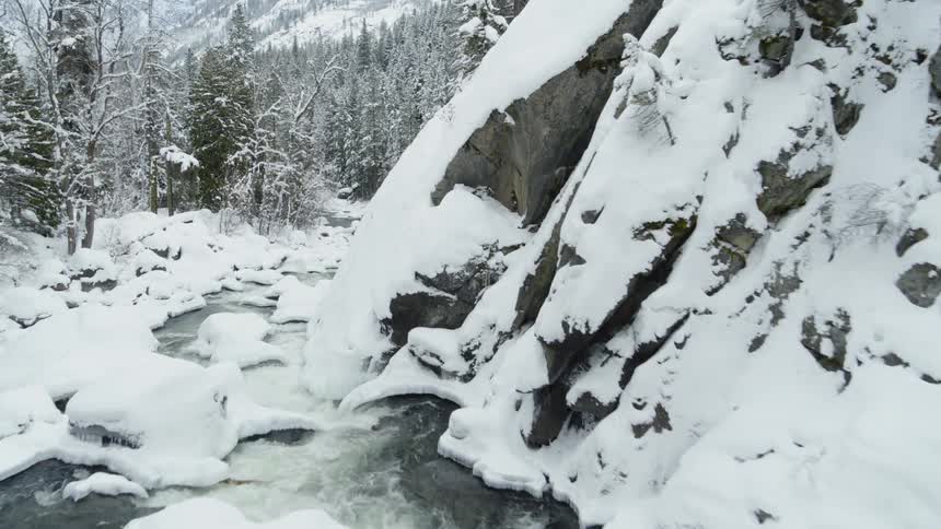 Flying downstream along a rugged and pristine snow covered mountain stream