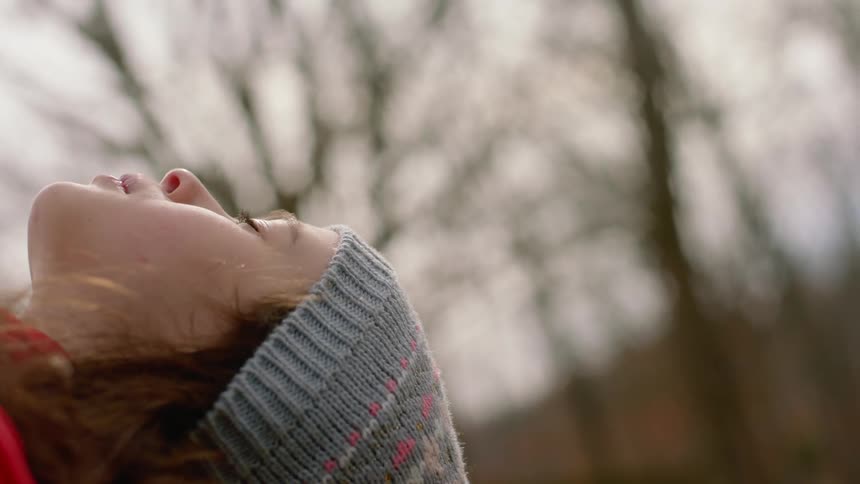 A young girl leans her head back while outside