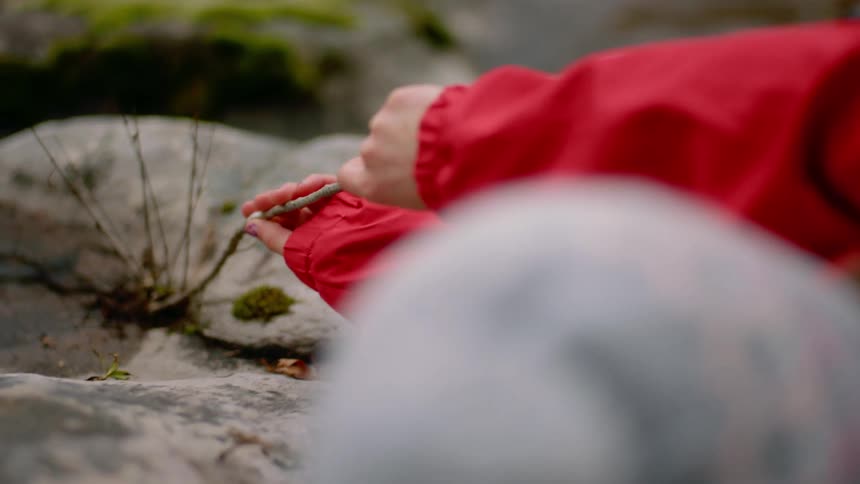A child is laying down digging under a rock