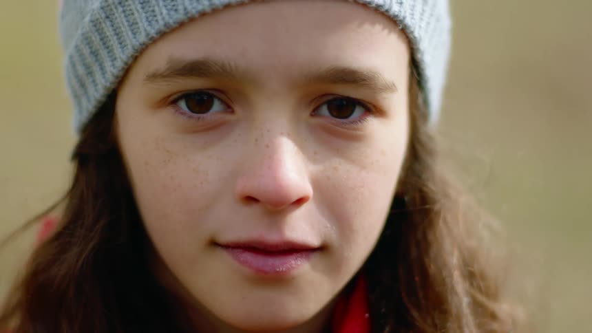 Girl with a grey beanie and brown hair faces the camera with eye contact