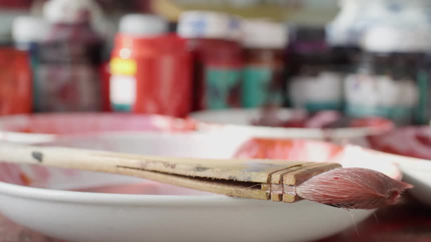 Jars of paint and a paint brush on a table