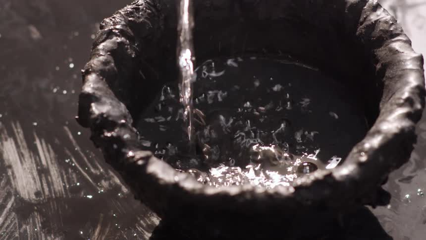 A person pours water out of a bottle in to a bowl
