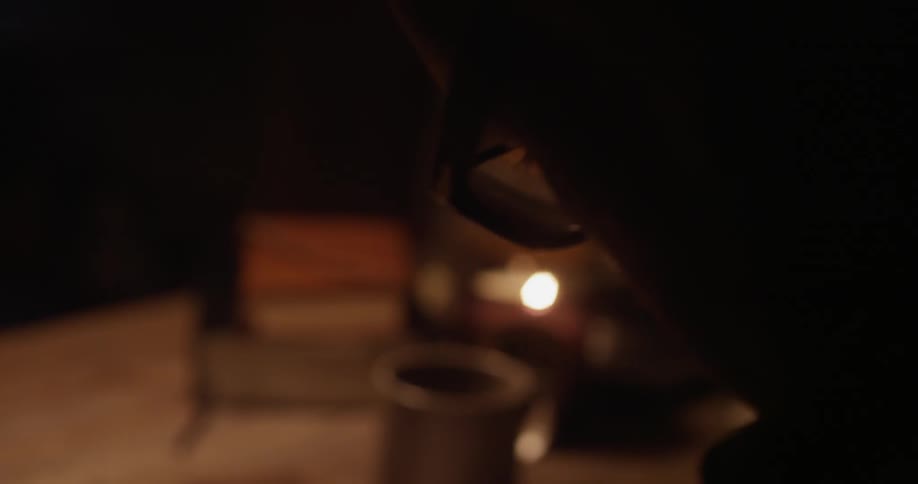 Spectacled person looking down at something while sitting at a table