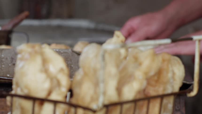 A chef fries dough in hot oil in a restaurant