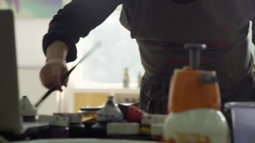 A man is mixing paint in his studio