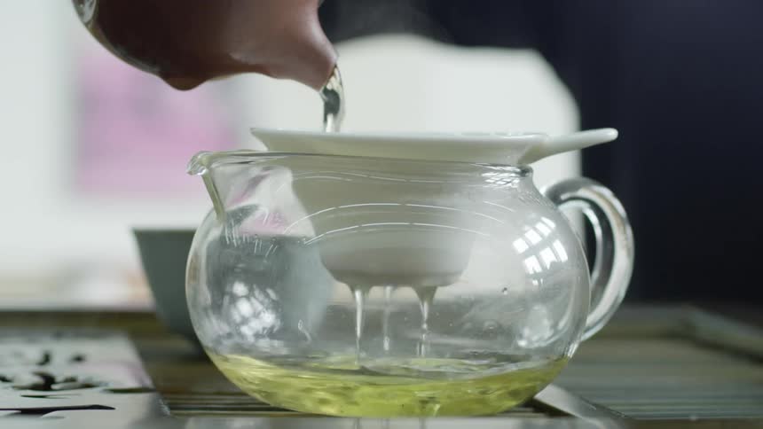 A person pours water in a teapot to steep tea
