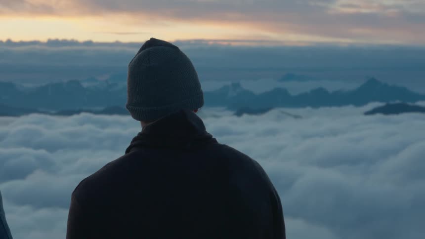 A man is high up on the mountain above the clouds