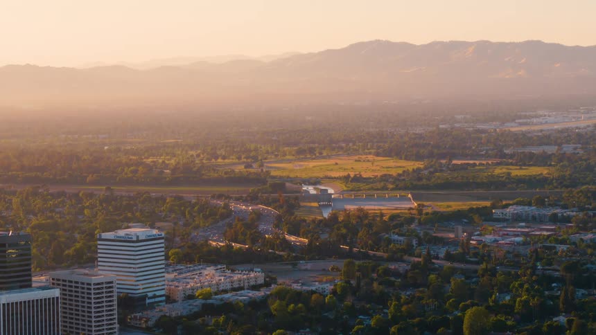 Aerial view of a small city on the plains next to a mountain range at sunset