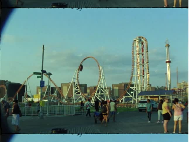 A roller coaster moving along its track at high speed at a busy fairground on the outskirts of a city