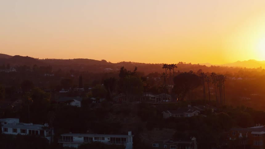Aerial view of the sun setting over a neighborhood in the hills