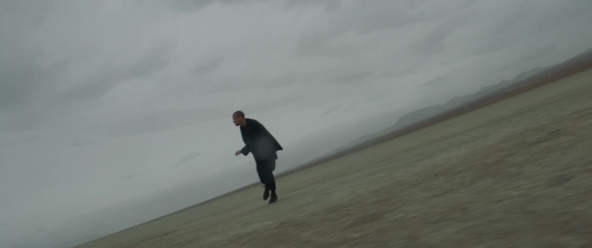 Man wearing all black dances on flat plains on a cloudy day