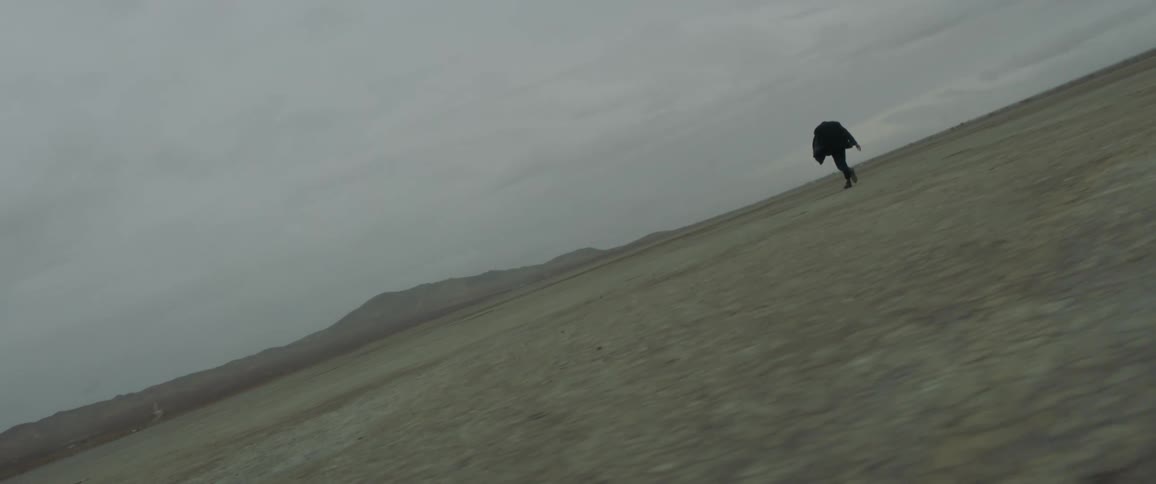 A man walks across a dirt field