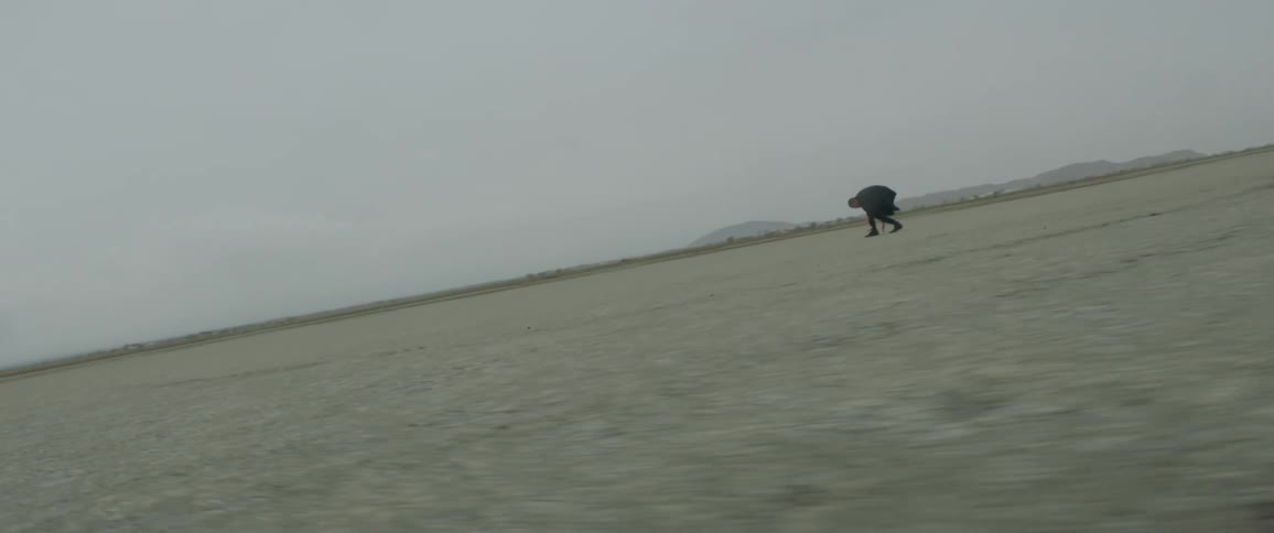 A man stumbles while walking on the desert sand