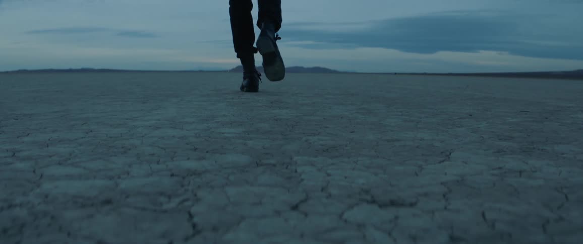 A man walks in a desert at dusk