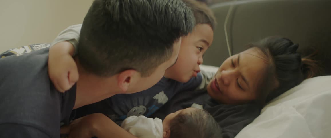 Man woman child and baby cuddle on a bed