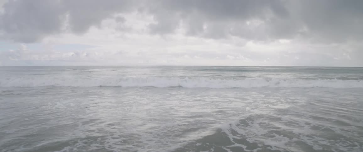 The large beach has waves hitting the sand